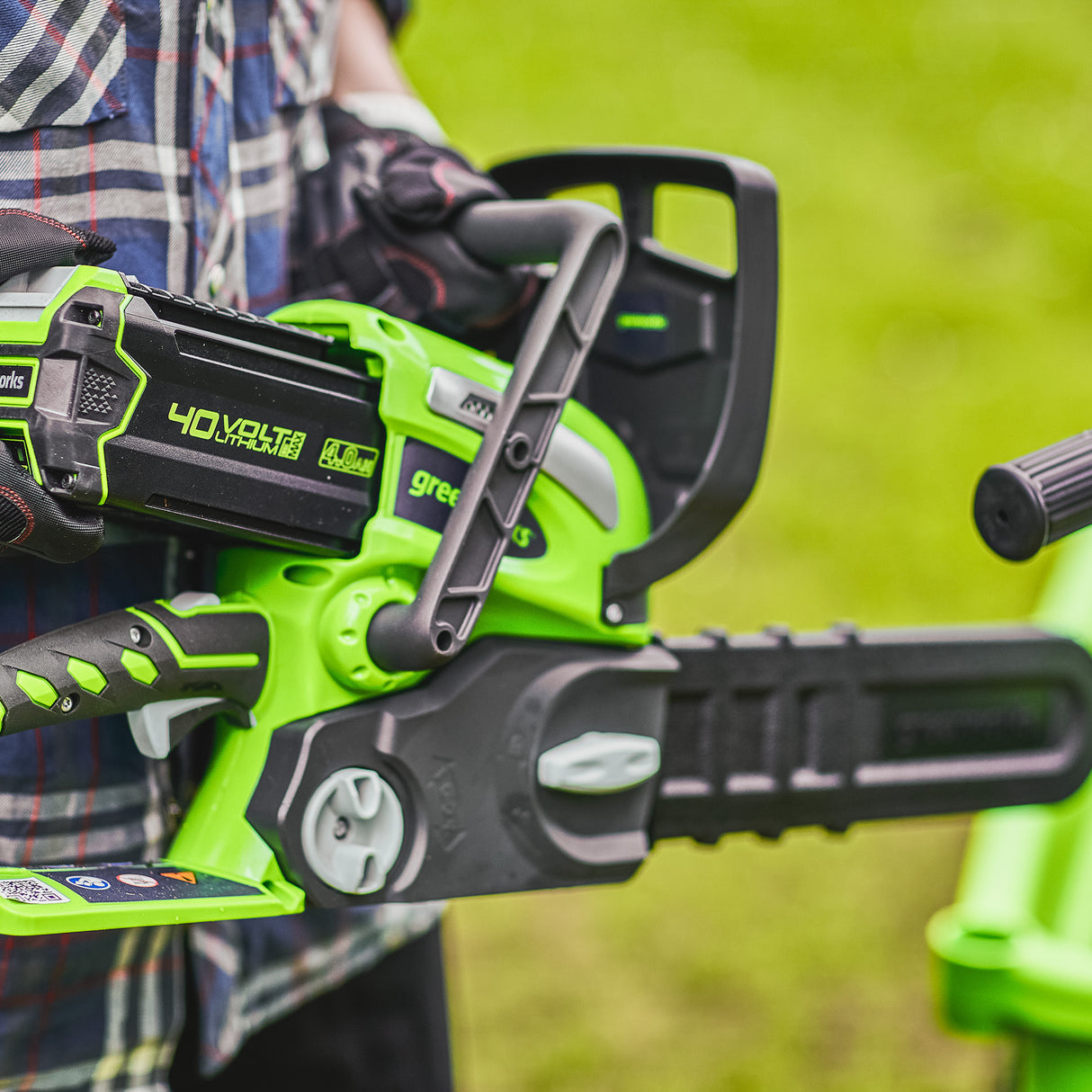 Green chainsaw held by a person with a blurred green background