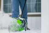Person using a green and black snow shovel to clear snow