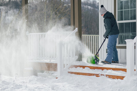 Person using a snow blower to clear snow from a porch