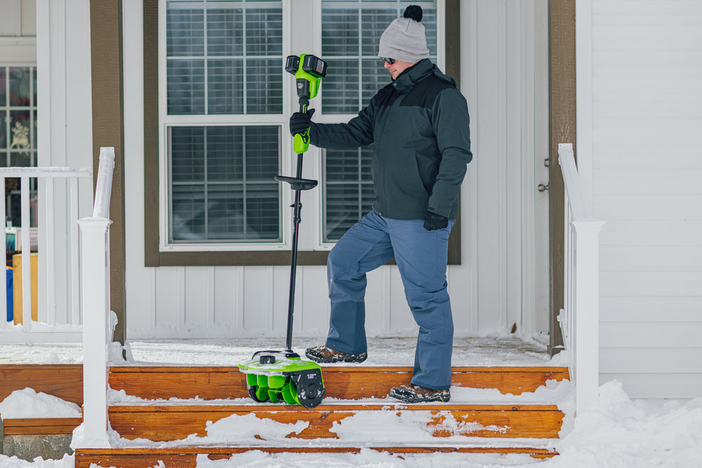 Person using a snow removal tool on a set of snowy steps.