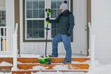 Person using a snow removal tool on a set of snowy steps.
