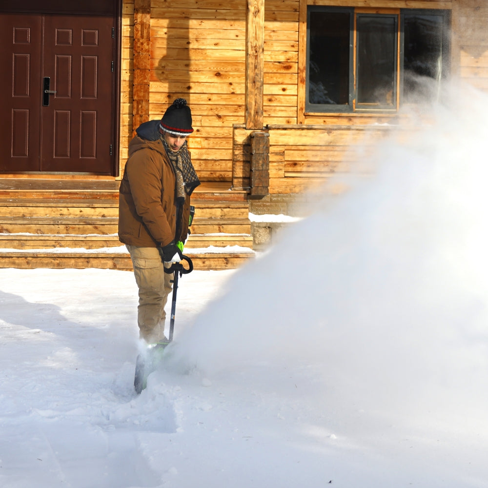 Person shoveling snow in front of a wooden cabin