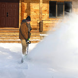 Person shoveling snow in front of a wooden cabin