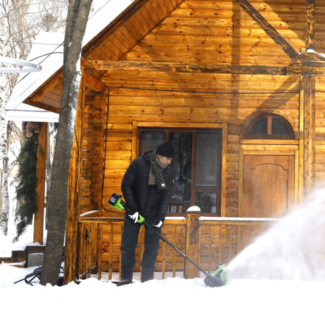 Person shoveling snow in front of a wooden cabin